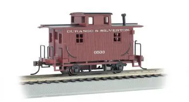 A red caboose on the tracks with a train car.