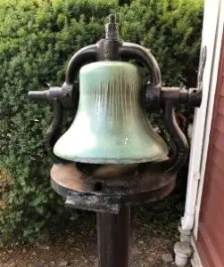 A bell is sitting on top of a pole.