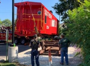 Two men standing next to a red caboose.