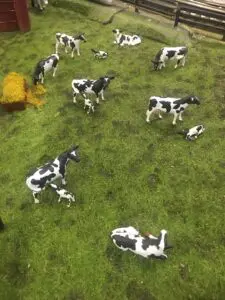 A group of cows in the grass with a yellow cart.