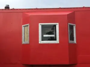 A red building with three windows on the outside.